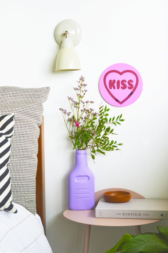 a sweet masterpiece inspired by classic love heart sweets. Featuring a prominent 'Kiss' message and blending pastel lilac color with pink metallic tones, this unique wall decor from our Love Collection is designed to infuse passion and charm into your space, creating a timeless addition that elevates home decor.